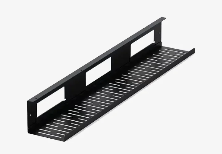 Black perforated steel under-desk cable tray on a plain background.