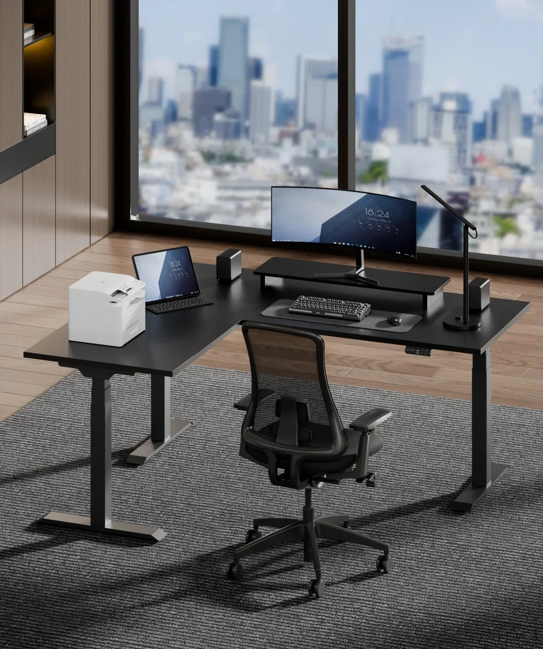 E7L electric standing desk. Black E7L corner desk with curved monitor, printer, tablet and mesh chair in a high-rise office overlooking a city skyline.
